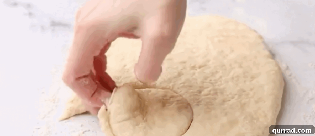 Buttery Flaky Homemade Biscuits 6 Close-up of a floured biscuit cutter being pressed straight down into flattened biscuit dough, forming individual round biscuits.