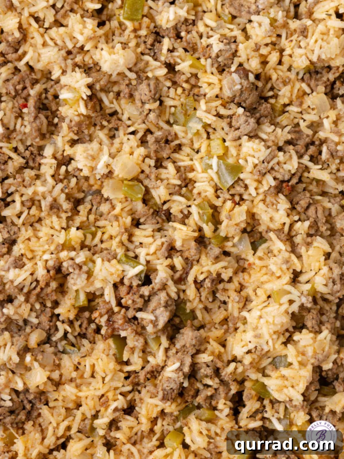Close-up of the ground beef and rice mixture browning in a skillet, before being transferred to a casserole dish, highlighting the savory texture.