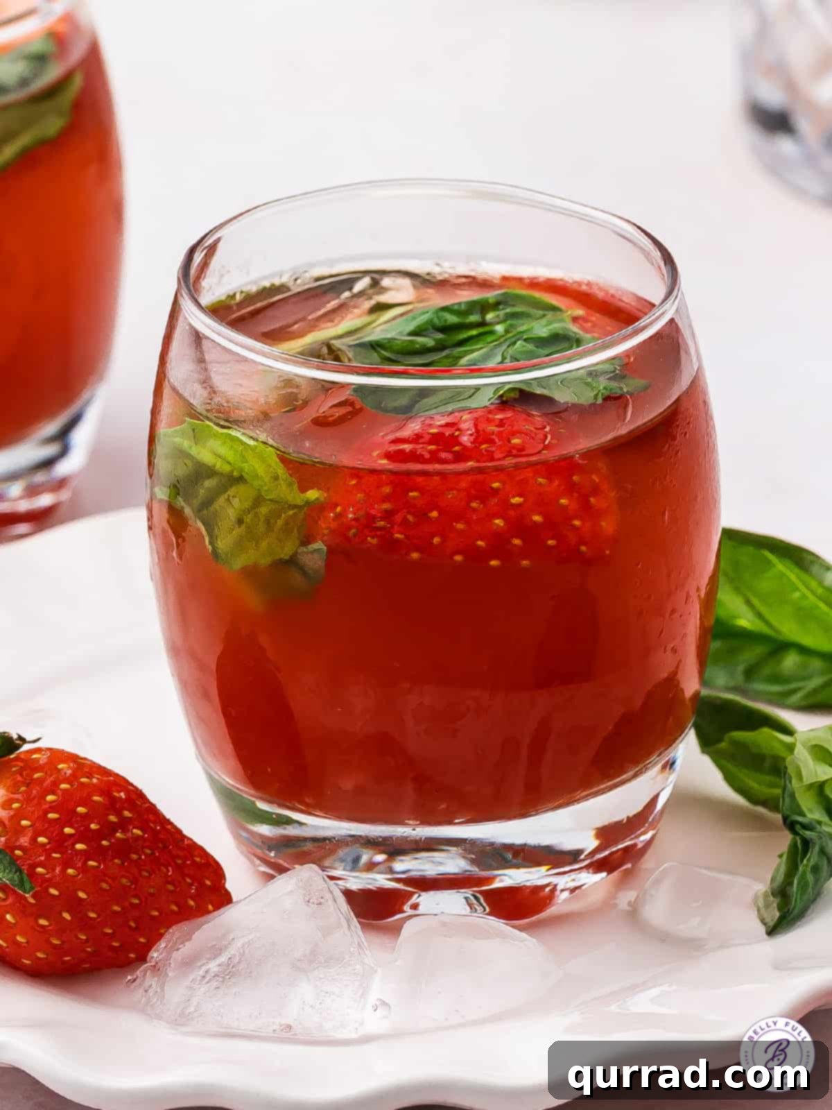 Experience the delightful fusion of strawberry, basil, and balsamic in this signature Ski Ya Later Cocktail. A vibrant red Ski Ya Later Cocktail with fresh strawberry and basil garnish, served in an elegant short glass.