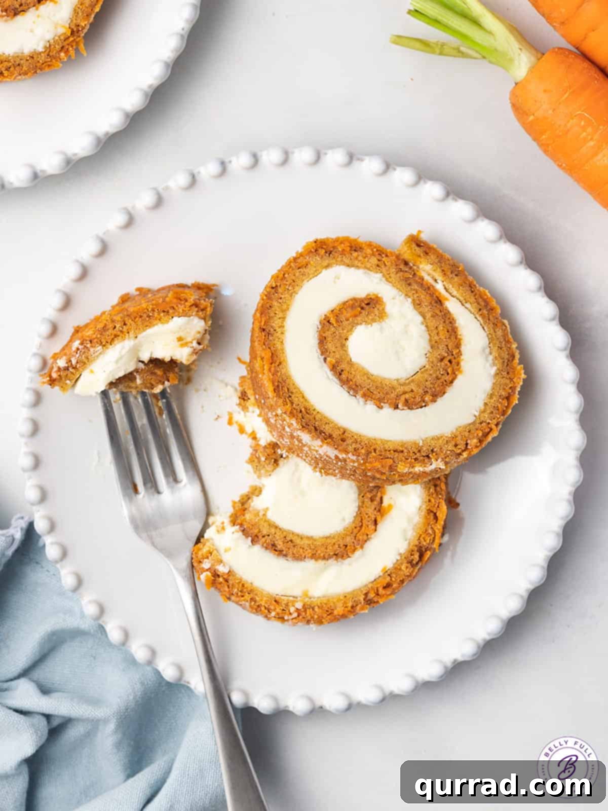 Spiced Carrot Cake Roulade 13 An overhead view capturing three perfectly cut slices of carrot cake roll on a simple white plate, ready to be enjoyed.