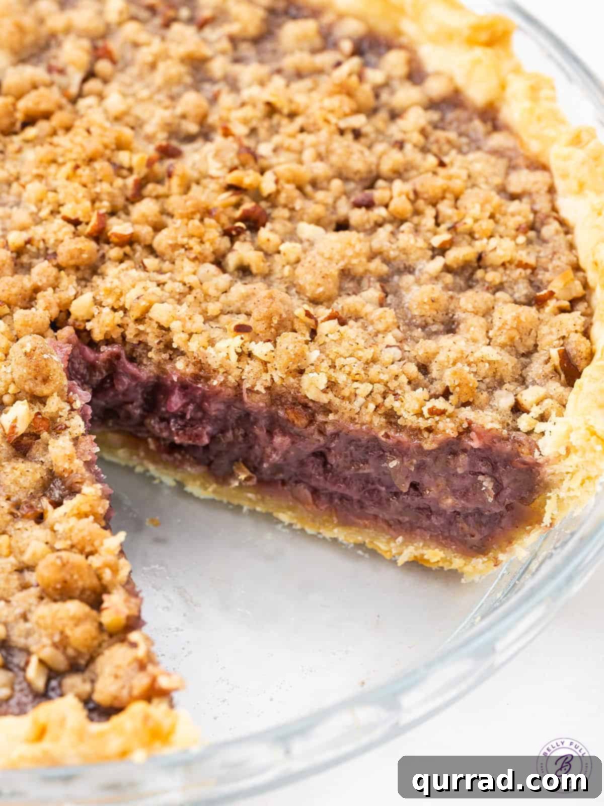 Homemade Grape Pie: A Classic Dessert with a Modern Twist A beautifully baked grape pie with one slice already cut out, ready to be served. The golden-brown streusel topping and vibrant purple filling are visible.
