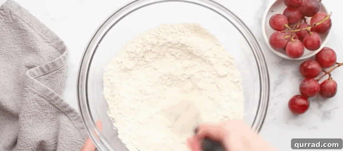 Step 1: Making the Pie Crust Base A close-up of a bowl where flour, salt, and sugar are being combined with cold butter cubes using a pastry cutter, forming coarse crumbs for the pie crust.
