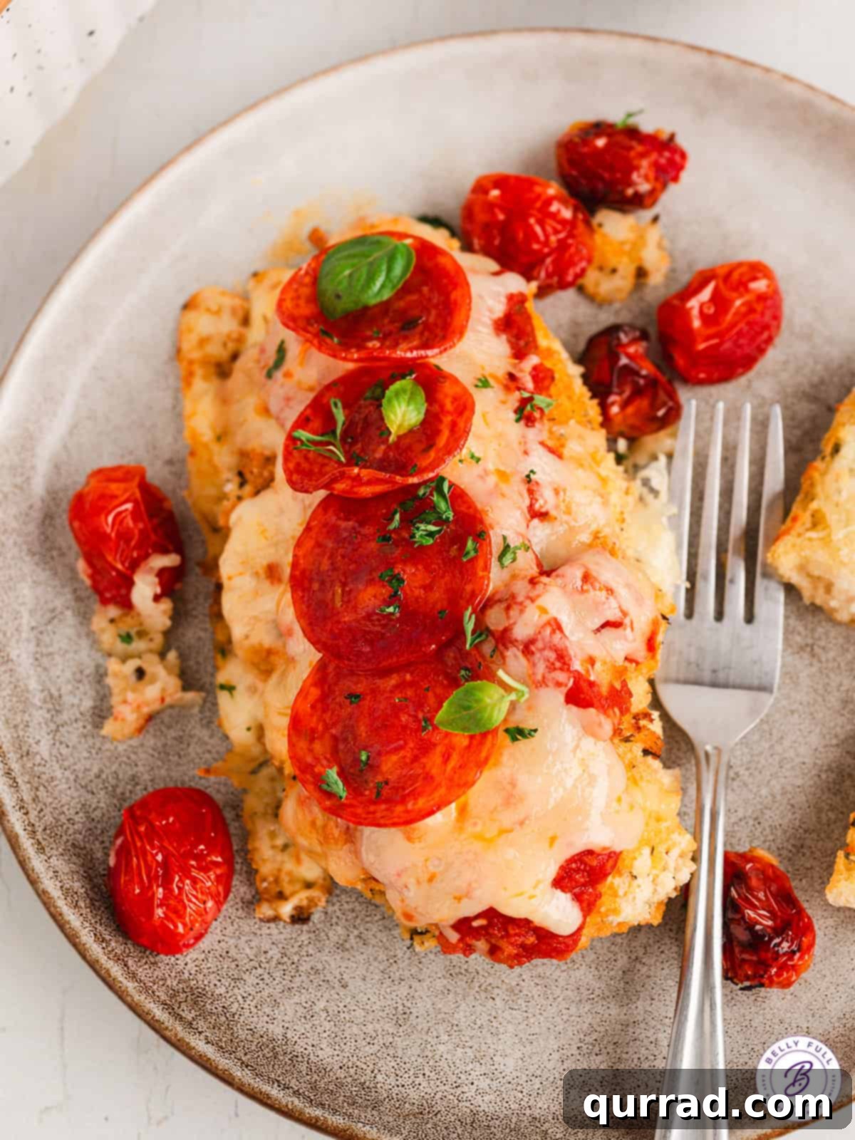 Individual serving of Pizza Parmesan Chicken A perfectly cooked piece of pizza parmesan chicken on a white plate, ready to be enjoyed