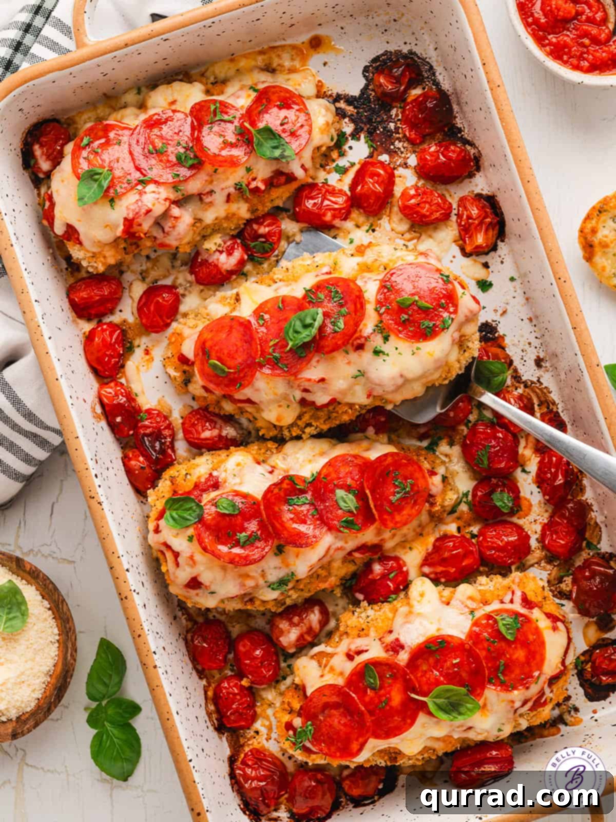 Pizza Parmesan Chicken baking in a dish An overhead view of pizza parmesan chicken cooking in a casserole dish, topped with marinara, mozzarella, and pepperoni