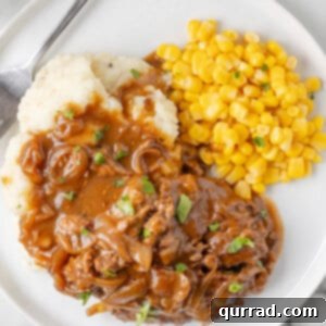 A plate of crockpot cube steak with mashed potatoes and corn