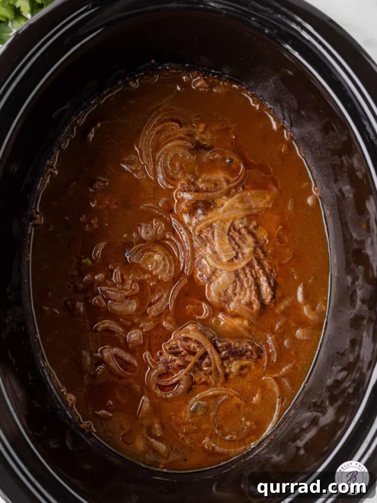 This Slow Cooker Cube Steak recipe features beef cube steaks browned then slow cooked all day with onions, gravy, and cream of mushroom soup. Cube steak in the slow cooker, simmering in the rich gravy.