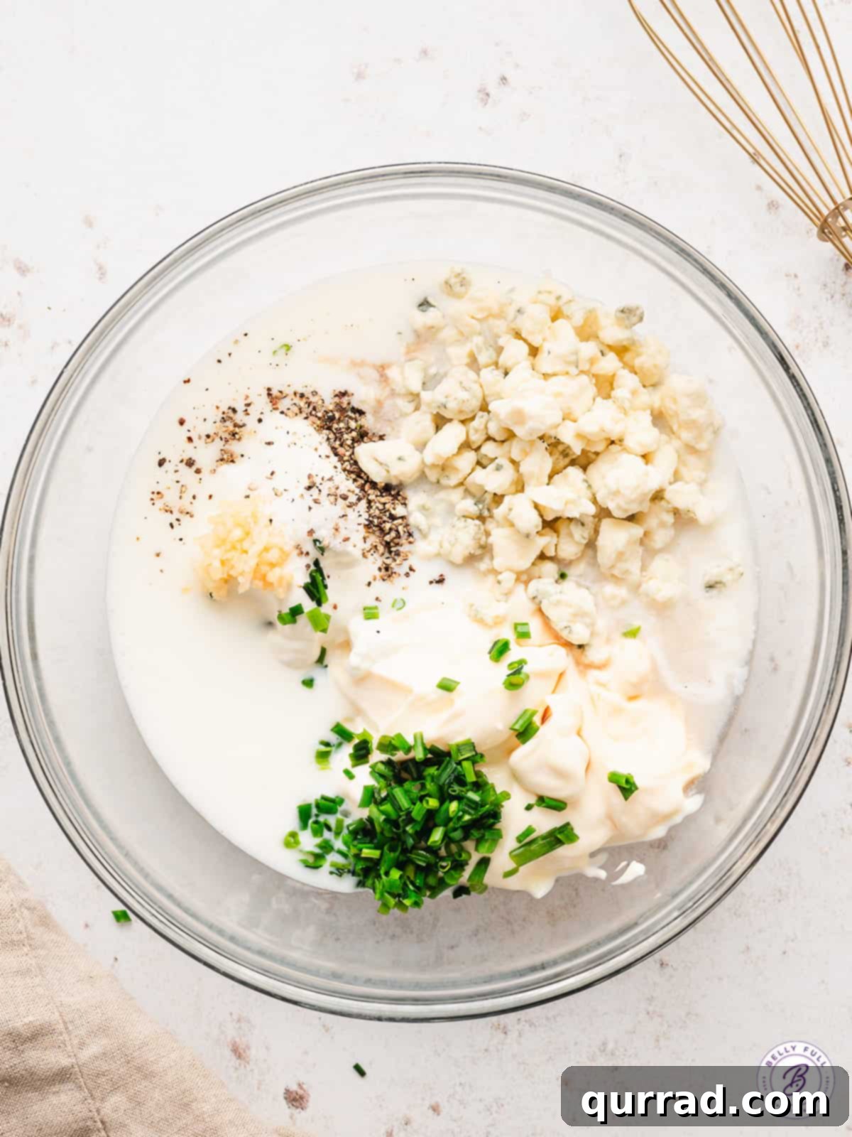 This Homemade Blue Cheese Dressing is made with blue cheese crumbles, buttermilk, sour cream, and a few other ingredients. Homemade blue cheese dressing ingredients in a bowl.