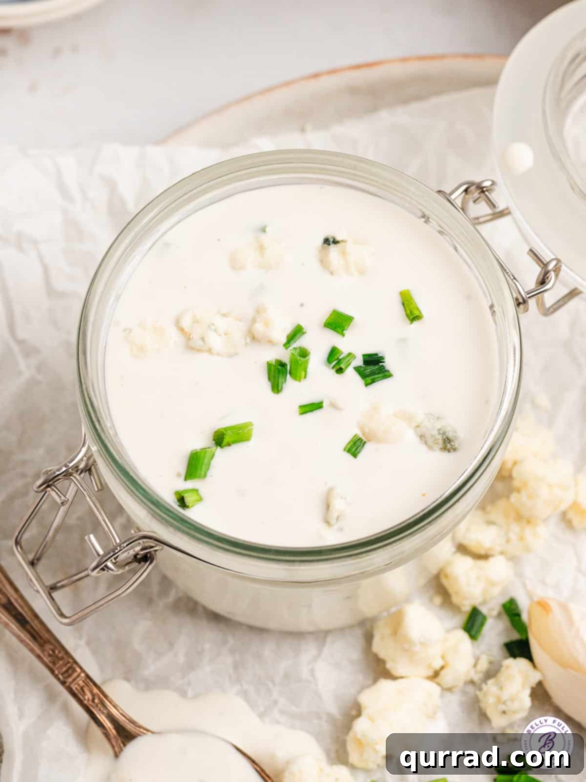 This Homemade Blue Cheese Dressing is made with blue cheese crumbles, buttermilk, sour cream, and a few other ingredients. Overhead view of a glass jar of blue cheese dressing.
