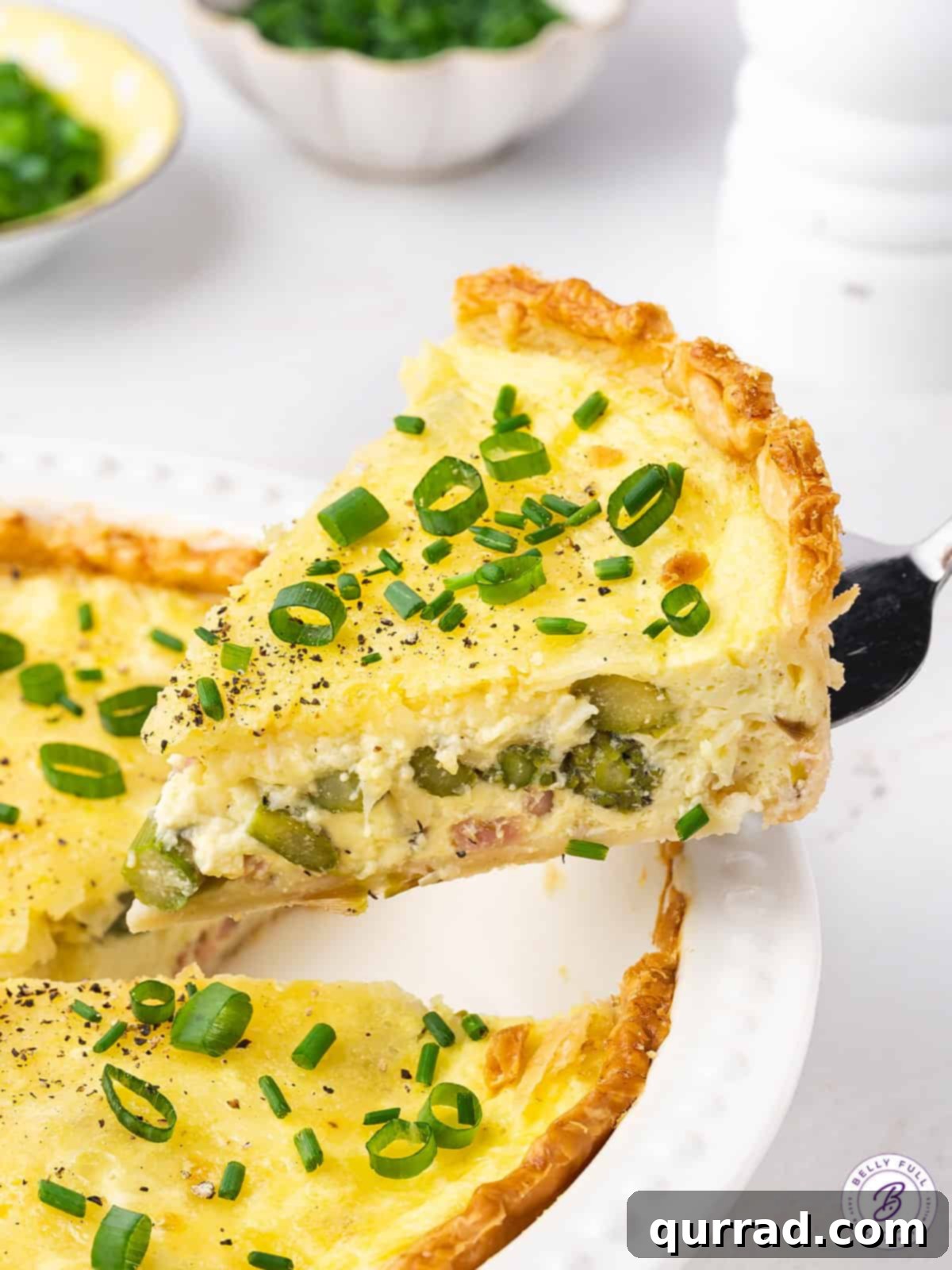 A beautifully served slice of homemade asparagus quiche with ham and Swiss cheese, ready to be enjoyed.