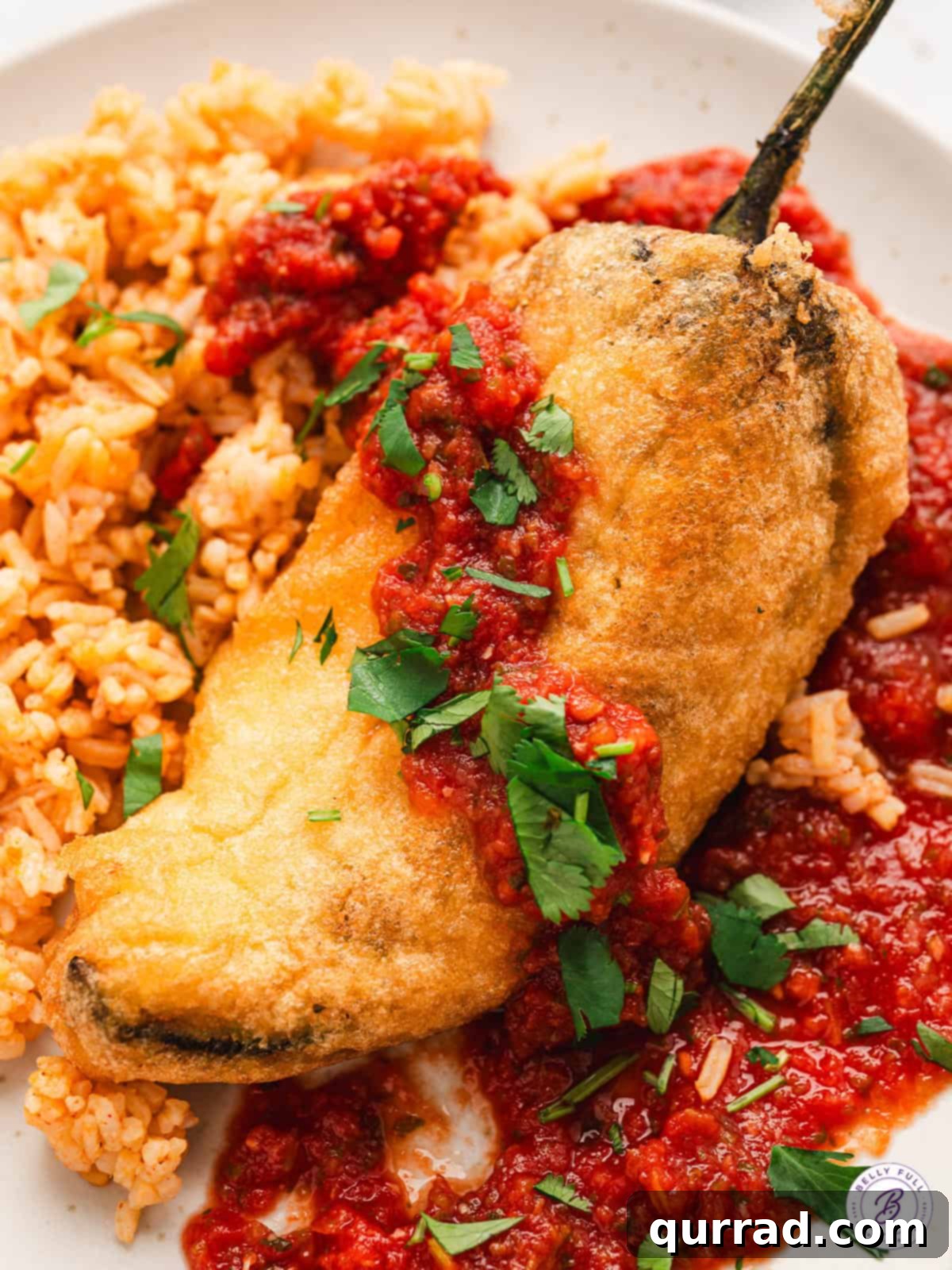 Classic Red Salsa 4 A vibrant red Salsa Roja drizzled generously over a perfectly battered and fried stuffed pepper (Chile Relleno), showcasing its versatility as a topping.