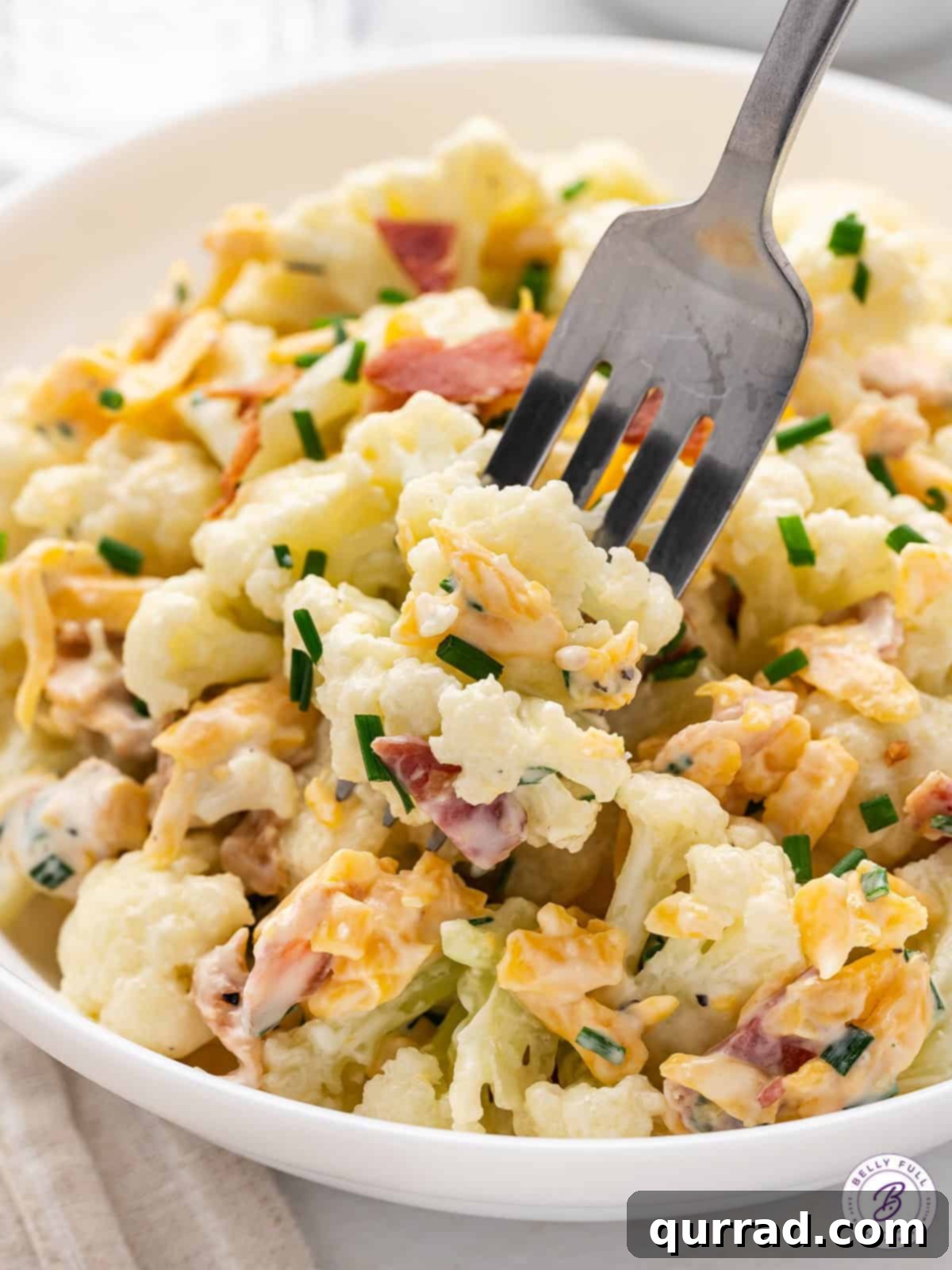 A fork diving into a bowl of cauliflower salad.