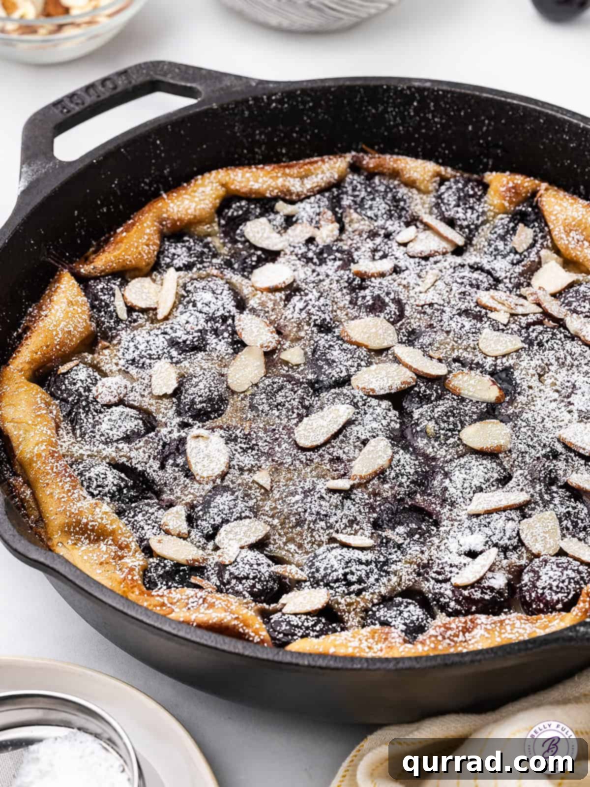 This Cherry Clafoutis recipe features a rich custard-like filling dotted with fresh tart cherries. Easy yet elegant! Cherry clafoutis in a cast iron skillet