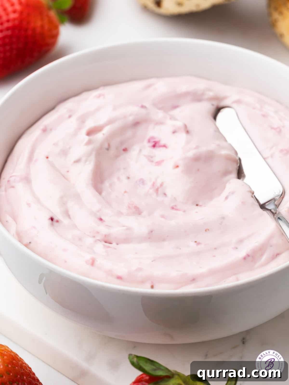 Made with fresh strawberries and powdered sugar, Strawberry Cream Cheese is light and fluffy with the perfect balance of sweet & tart flavors. Homemade strawberry cream cheese in a white bowl, ready to be served, showcasing its vibrant pink color and creamy texture.
