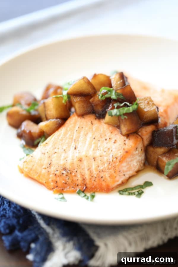 Cooked salmon fillets topped with a generous serving of sautéed apples, showcasing the beautiful golden-brown crust of the fish.