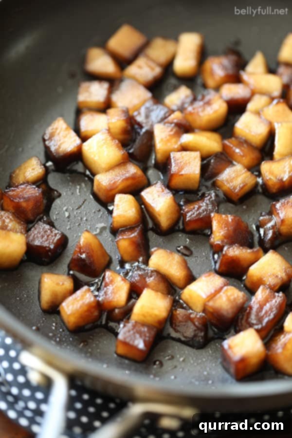 A close-up of sautéed apples simmering in a sweet and tangy balsamic and honey glaze, ready to top broiled salmon.