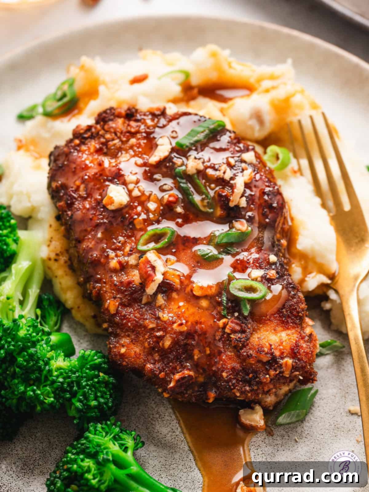A pecan crusted chicken breast on a plate with potatoes and broccoli, showcasing the golden crust and rich sauce.