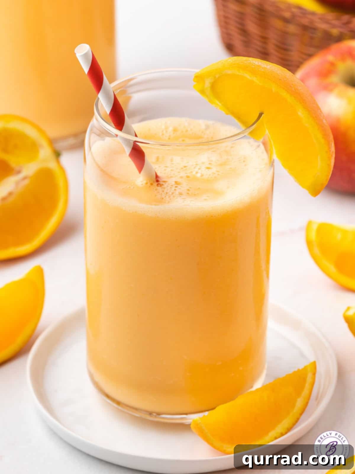 Liquid Sunshine 2 Vibrant orange smoothie served in a glass with a straw and an orange wedge, ready to be enjoyed.