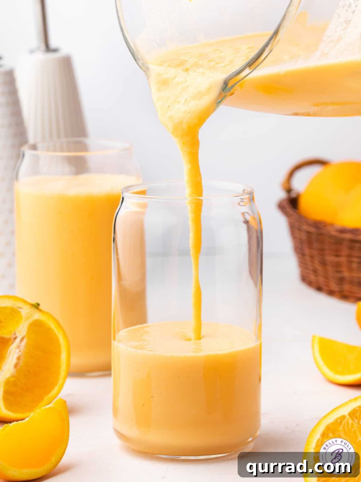 Liquid Sunshine 4 Thick orange smoothie mixture being poured from a blender into a glass, showcasing its smooth texture.