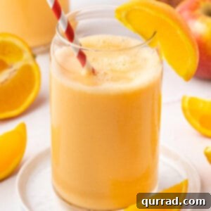 orange smoothie with straw and orange wedge