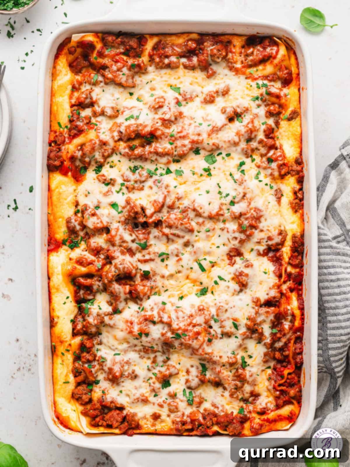 Lazy Day Lasagna is made with no-cook noodles, ricotta filling, and meat sauce. The easy lasagna recipe you didn't know you were missing! Overhead view of lazy day lasagna, showcasing its golden-brown top and rich layers