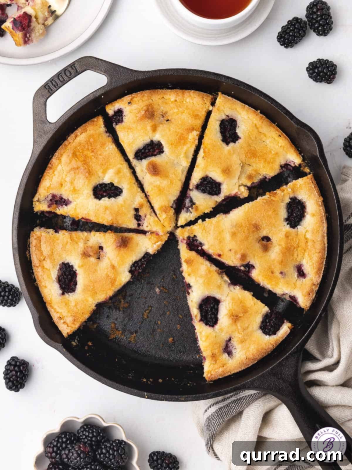 Luscious Blackberry Delight 2 A perfectly sliced blackberry cake, rich with berries, displayed in a rustic cast iron skillet.