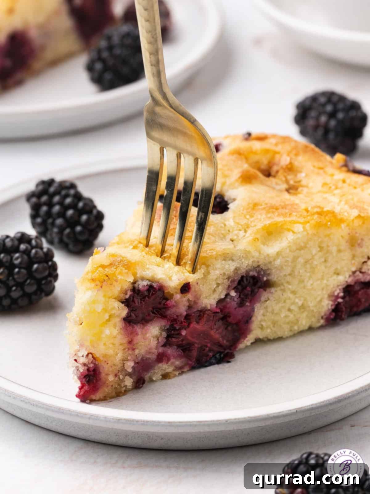 Luscious Blackberry Delight 10 A fork taking a slice from a freshly baked blackberry cake, showcasing the moist interior and plump berries.
