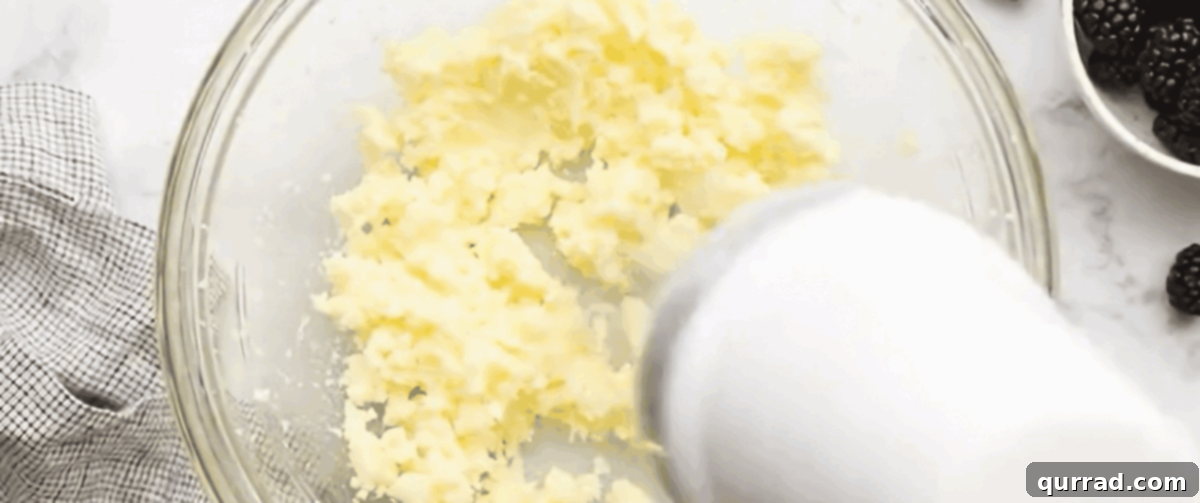 Luscious Blackberry Delight 4 Creaming softened butter and granulated sugar together in a glass bowl using an electric hand mixer, creating a light and fluffy mixture.