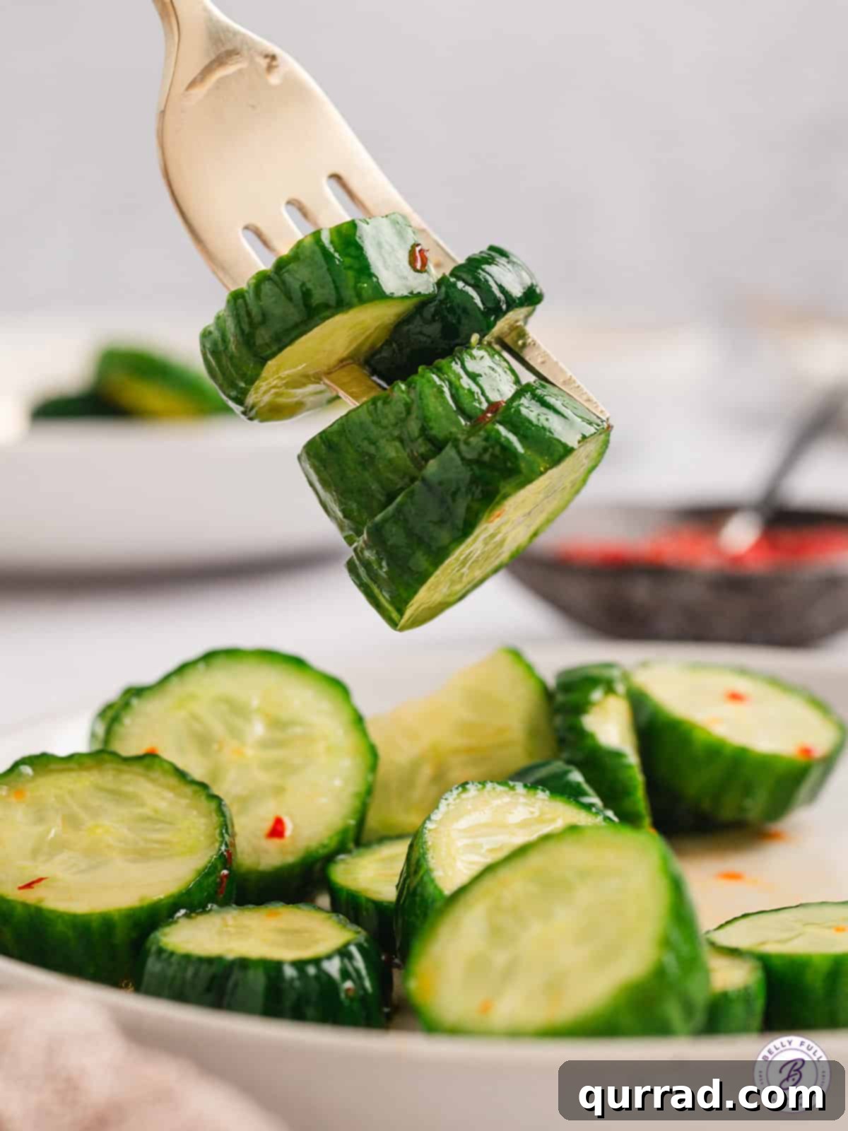 Zesty Asian Cucumber Crunch 3 Four thick slices of marinated Asian cucumbers on a fork, highlighting their appealing texture.