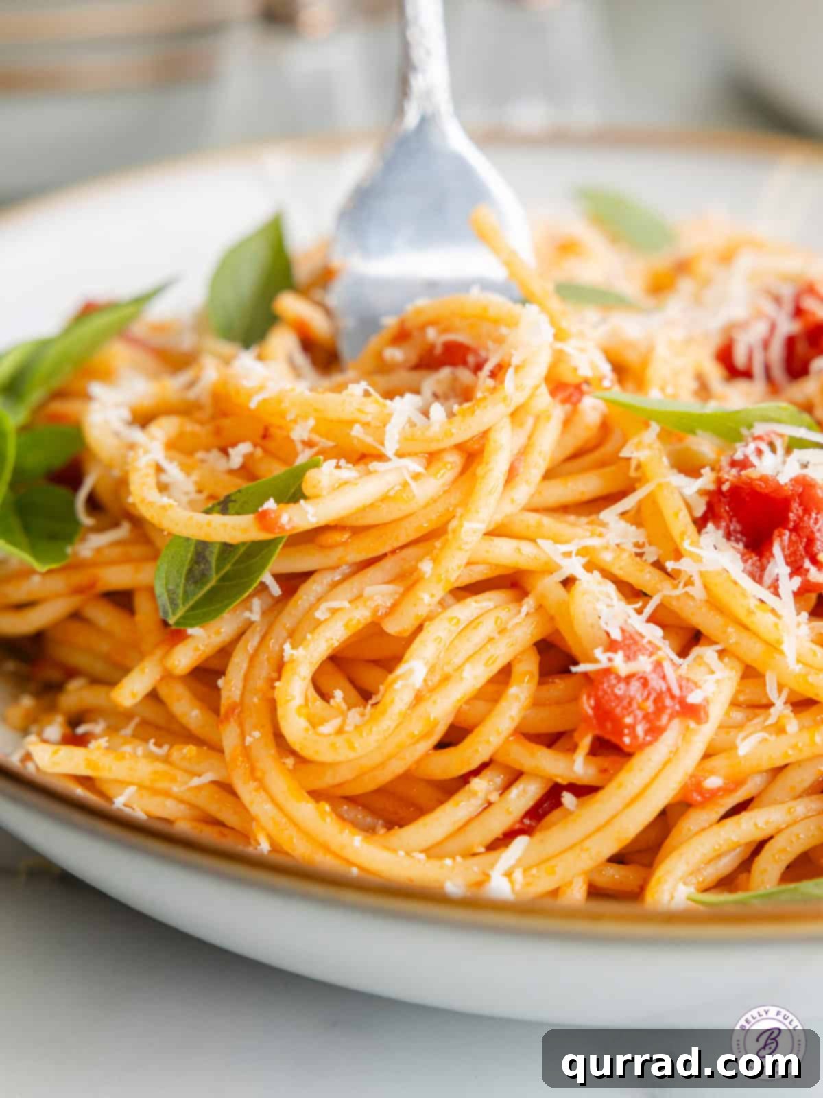 Experience the deliciousness of Pasta Pomodoro: al dente spaghetti coated in a simple yet incredibly flavorful tomato, garlic, and basil sauce. A fork perfectly twisted with a generous bite of Pasta Pomodoro, ready to be eaten, showcasing the rich sauce and perfectly cooked spaghetti.