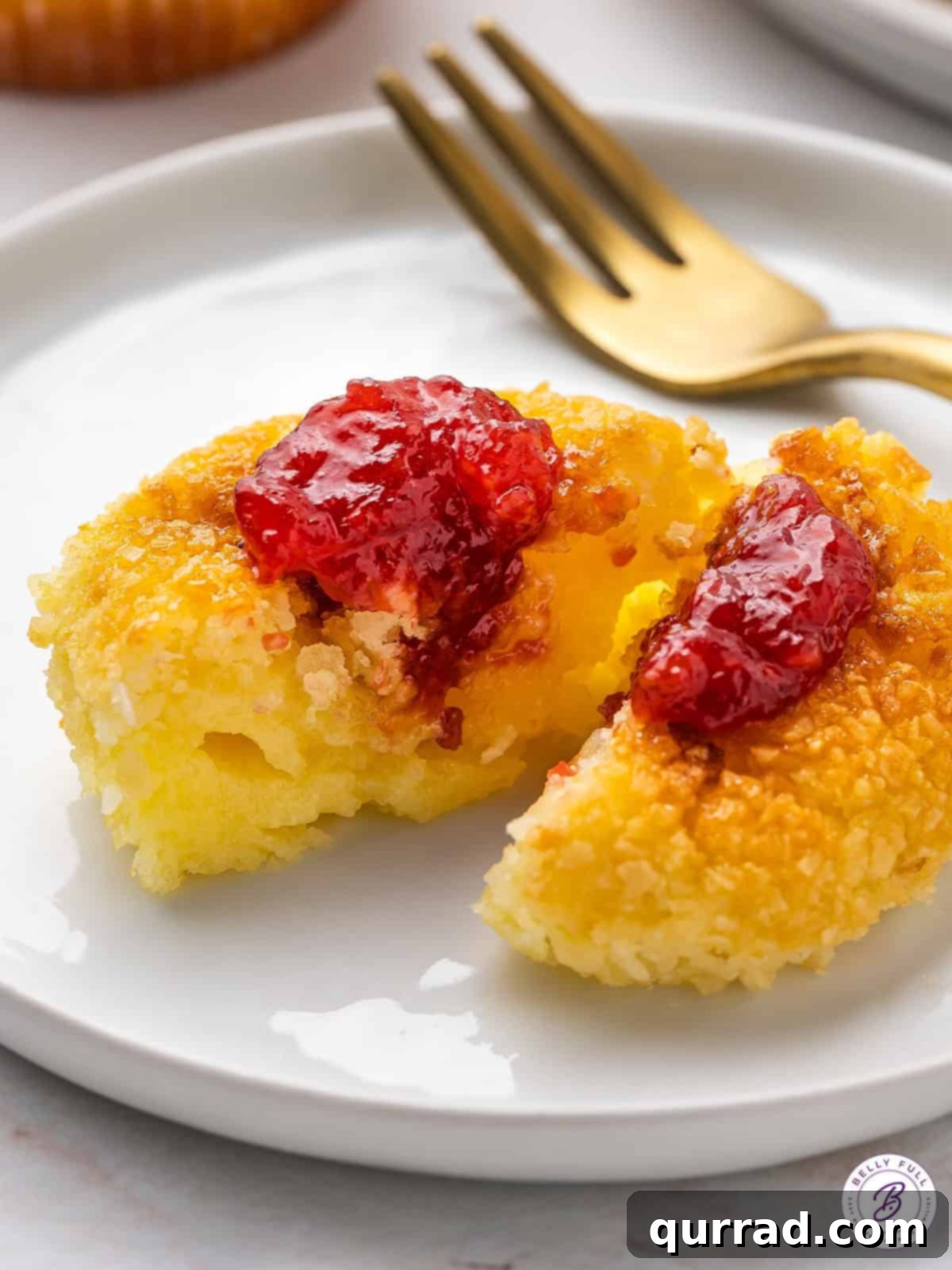 A cross between a creamy custard tart and an eggy macaroon, these Mini Coconut Cakes are a popular Portuguese dessert. A Portuguese mini coconut cake, cut in half to reveal its rich, creamy custard interior and textured coconut layers.