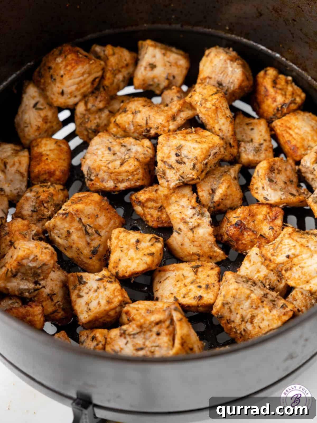 Tossed with Worcestershire sauce and a few spices, these Air Fryer Pork Chop Bites are tender, juicy, and perfectly seasoned. Pork chop bites cooking in an air fryer basket, showing even browning