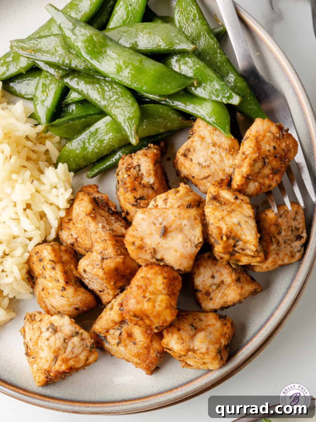 Tossed with Worcestershire sauce and a few spices, these Air Fryer Pork Chop Bites are tender, juicy, and perfectly seasoned. Plate of air fryer pork chop bites served with green snap peas and rice