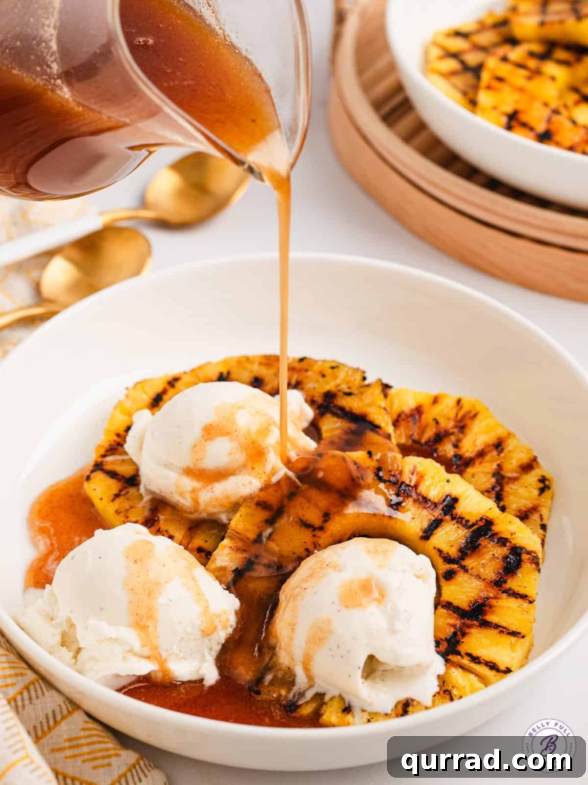 Drizzle this sweet and citrusy Pineapple Rum Sauce over grilled pineapple and vanilla ice cream for a perfect treat. Close-up shot of Pineapple Rum Sauce being generously drizzled over a plate of grilled pineapple slices and a scoop of vanilla ice cream