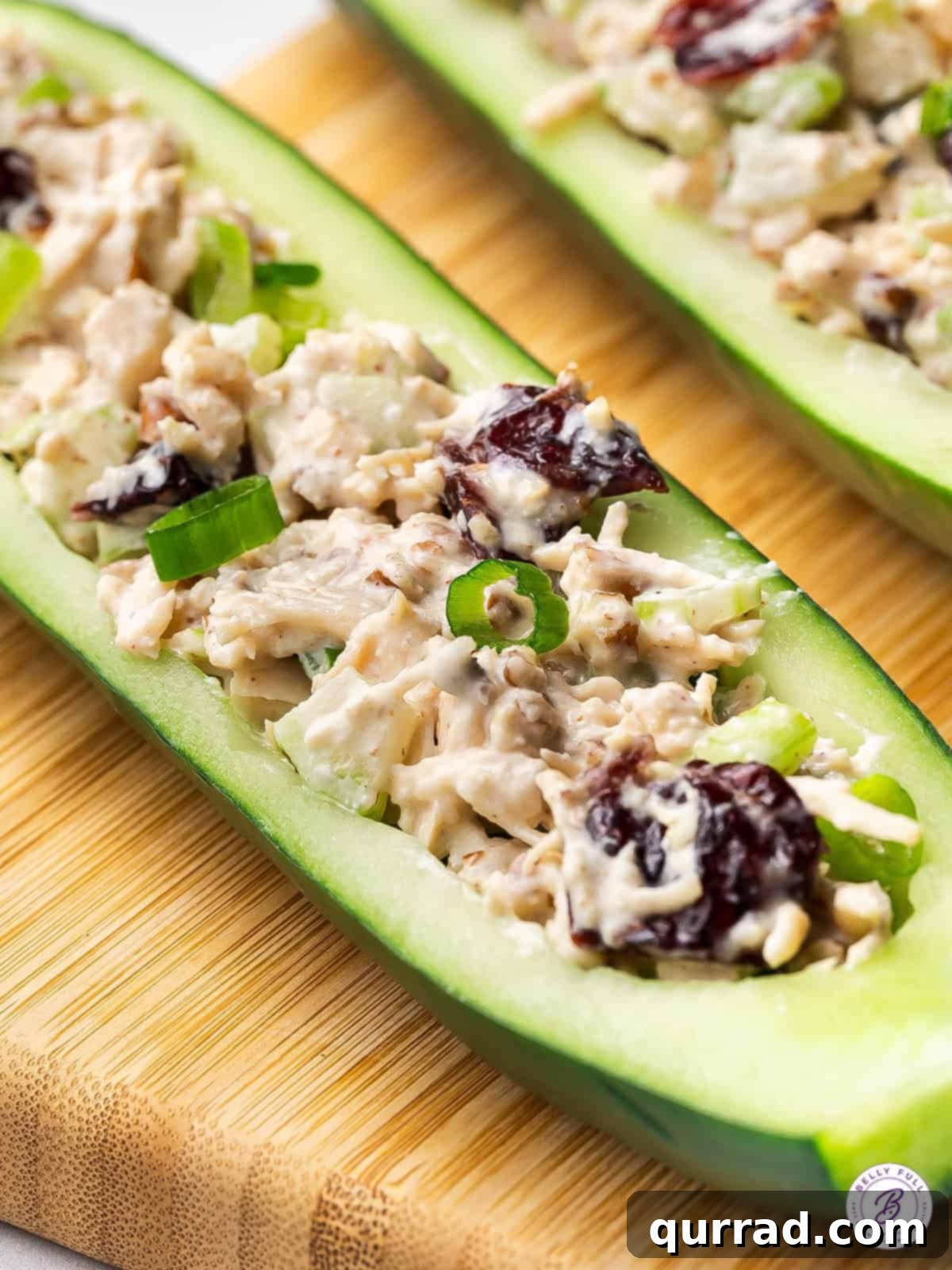 Cool, crunchy, and refreshing, these Chicken Salad Cucumber Boats are a fun and low-carb way to enjoy chicken salad. Easy lunch or snack! Close up of a cucumber boat with chicken salad, showing the vibrant ingredients