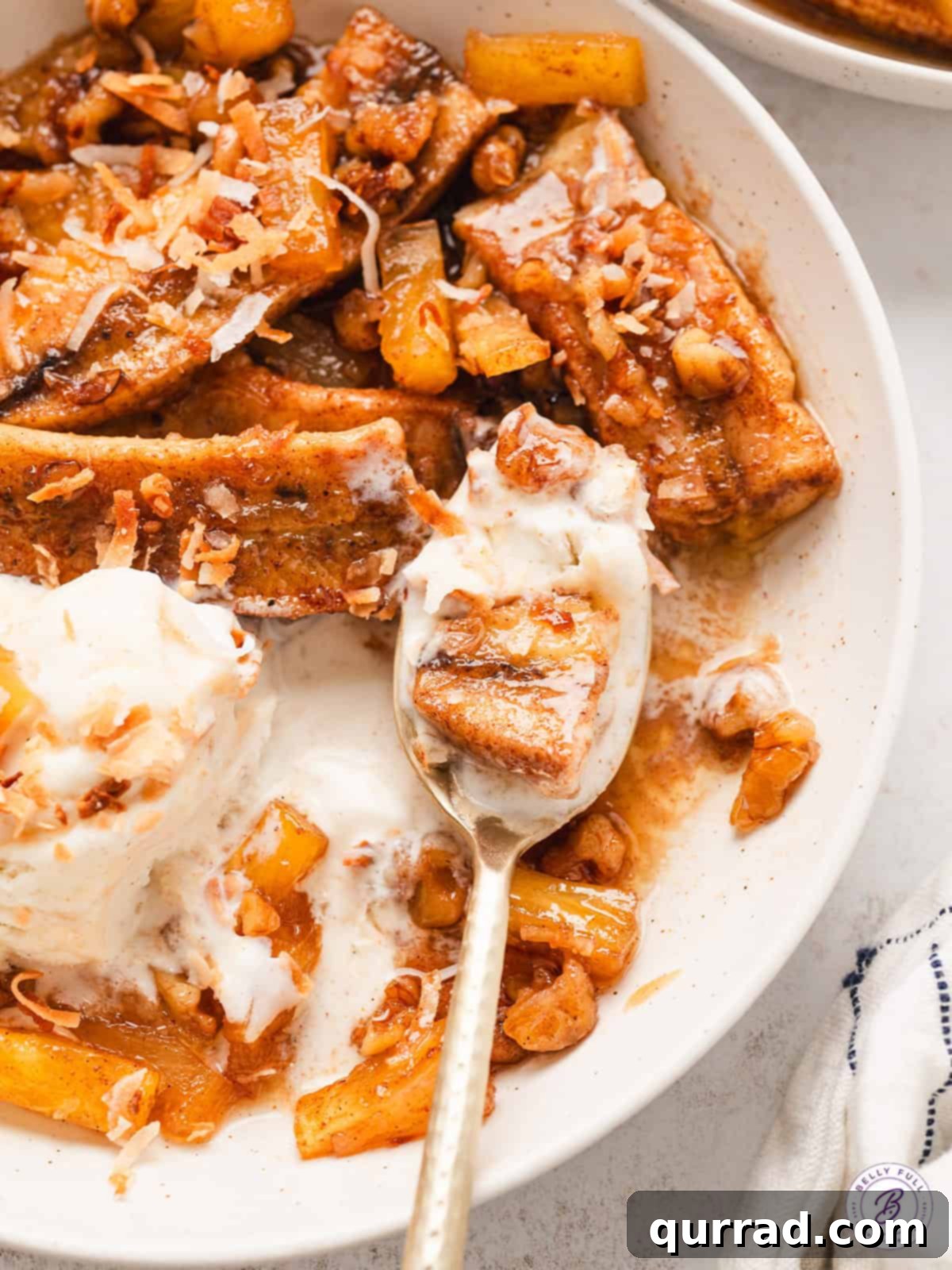 A beautifully presented bowl of crockpot pineapple bananas foster with ice cream, wafers, and coconut.