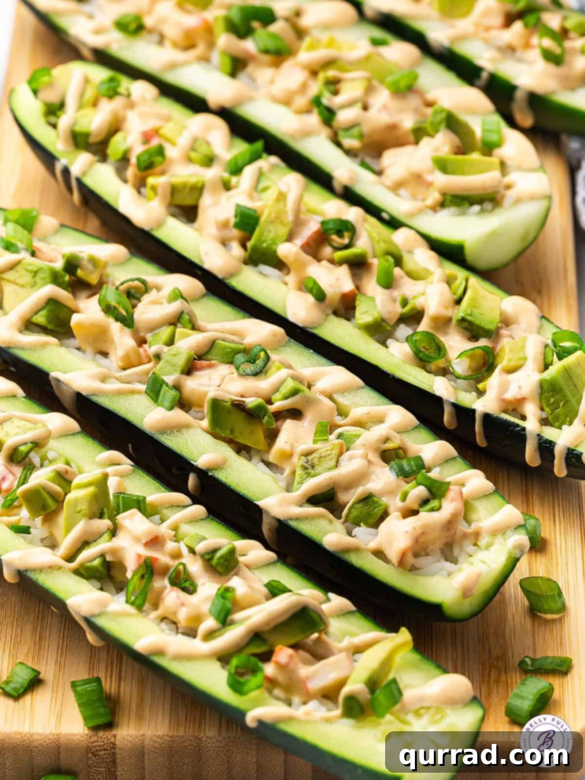 Experience the best elements of sushi without the hard work with these delightful crab-filled Cucumber Sushi Boats. Overhead view of vibrant cucumber sushi boats filled with spicy crab and rice, garnished with avocado and scallions, presented on a light platter.