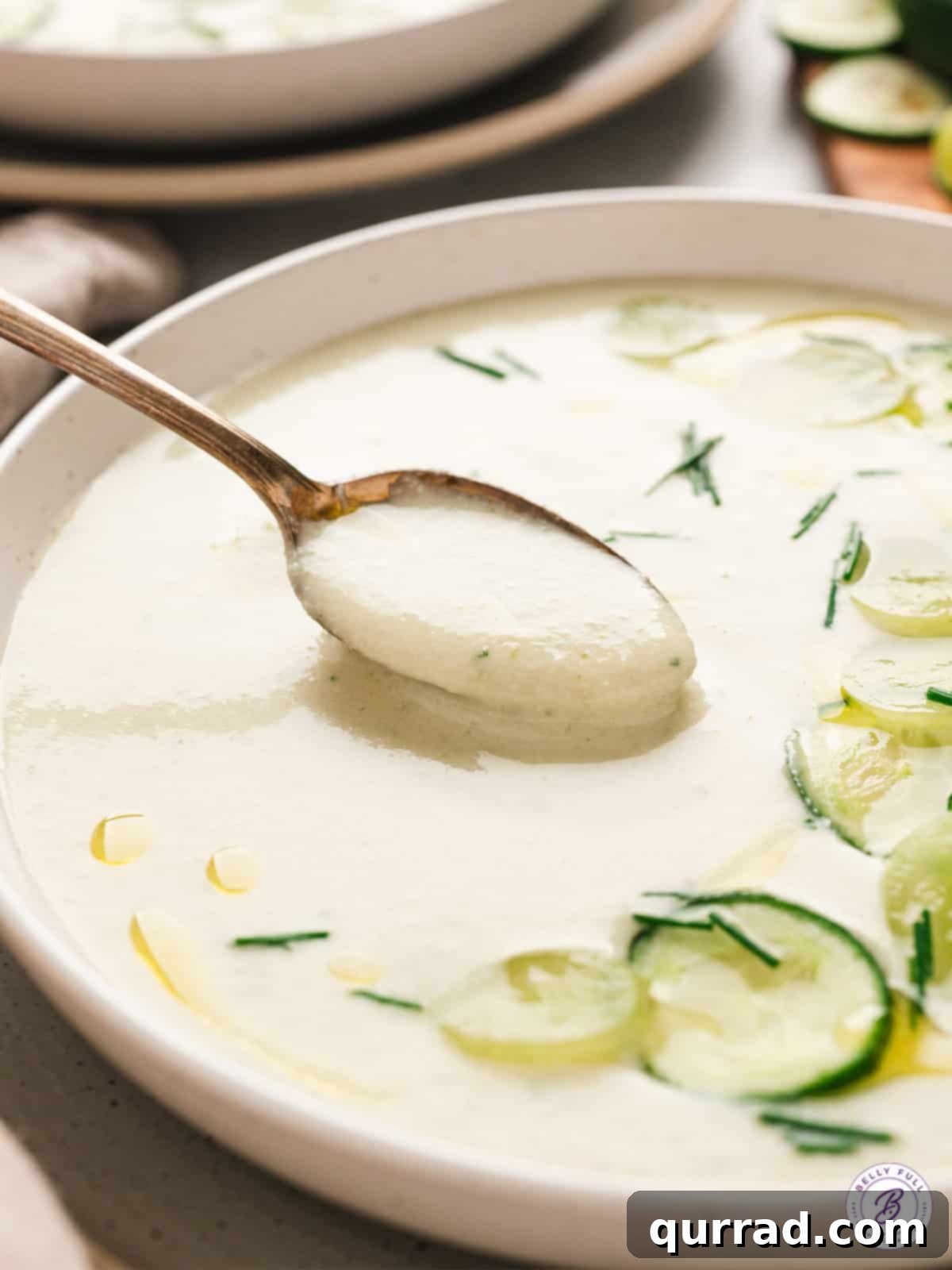 A silver spoon dipped into a bowl of cold cucumber soup, capturing the rich, creamy texture and vibrant color, ready to be enjoyed.