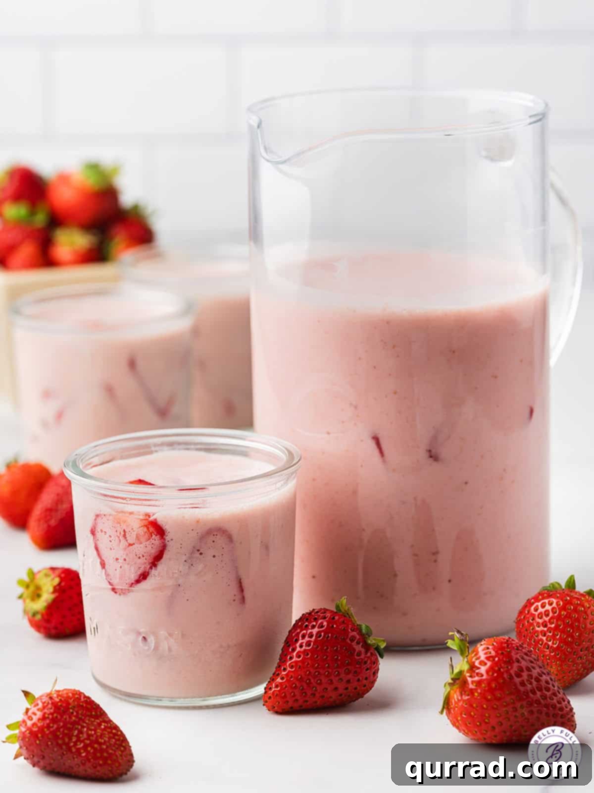 Refreshing Pitcher of Strawberries and Cream Agua Fresca for Summer Gatherings A pitcher overflowing with Strawberries and Cream Agua Fresca, accompanied by two glasses ready to be poured, capturing the essence of a refreshing summer beverage.