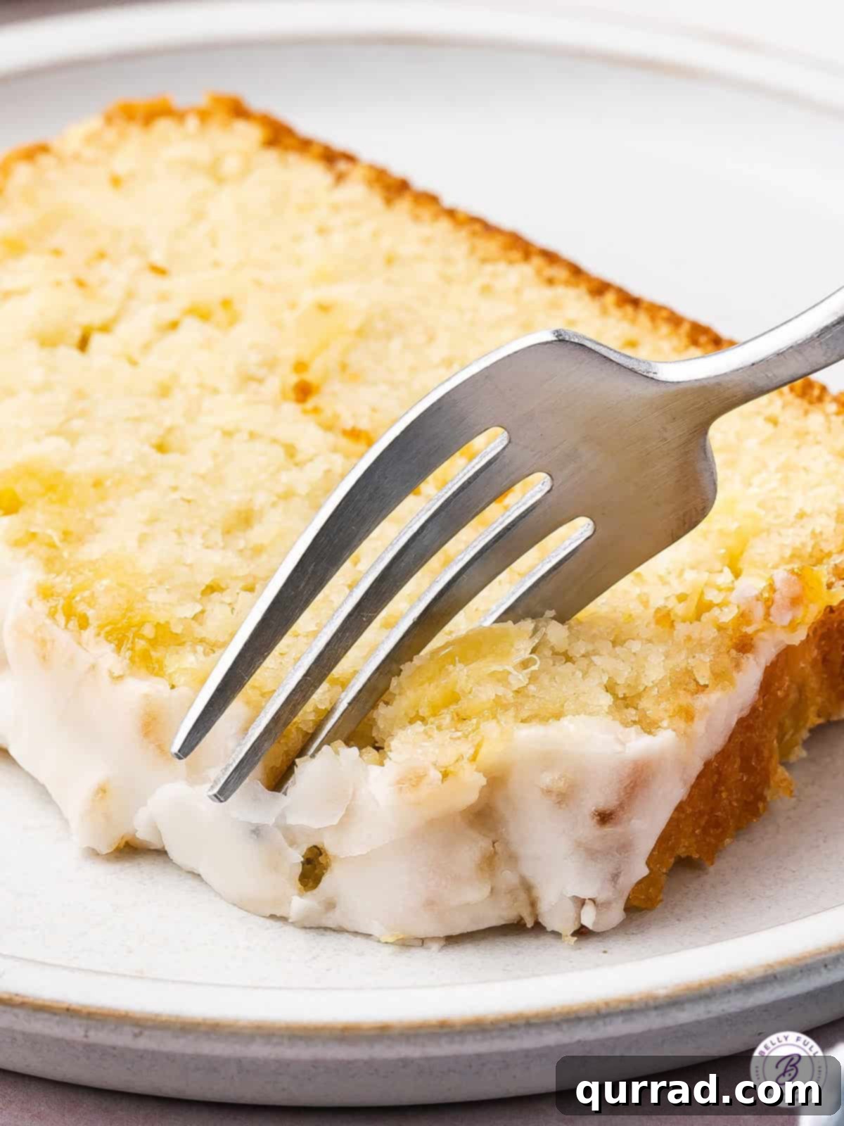 A fork delicately cuts into a thick slice of freshly baked, glazed pineapple bread, revealing its moist interior and inviting texture.