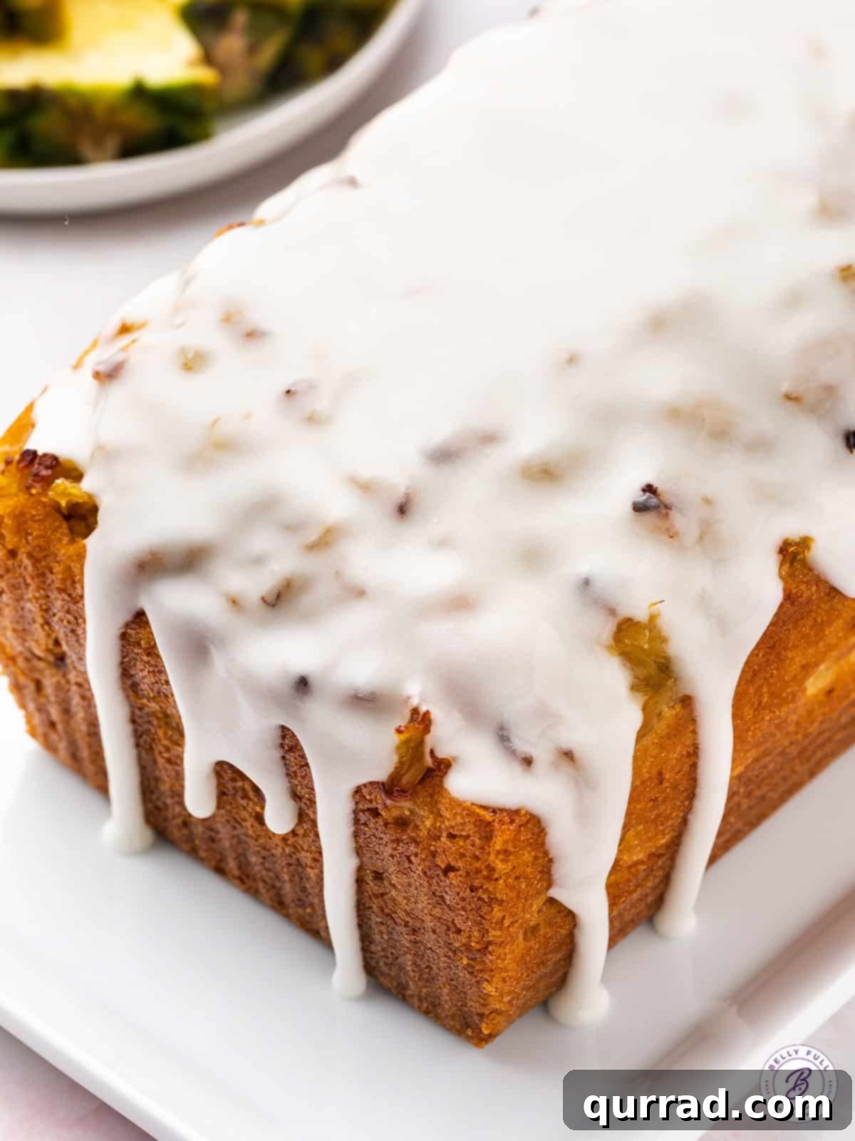 A whole loaf of freshly baked pineapple bread, generously covered in a white glaze, sitting on a wooden cutting board with a few slices already cut.