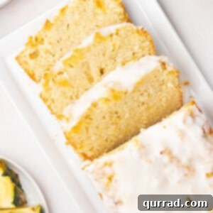 A perfectly baked loaf of Pineapple Bread, lightly glazed and ready to slice, sits elegantly on a cooling rack.