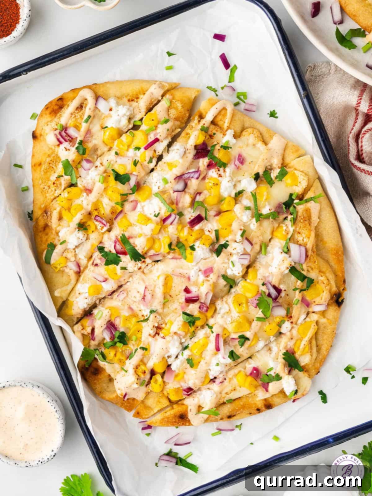 With a seasoned Mexican crema sauce, corn kernels, red onions, and lots of cheese, this Mexican Street Corn Flatbread is a fun appetizer. Overhead view of Mexican street corn flatbread