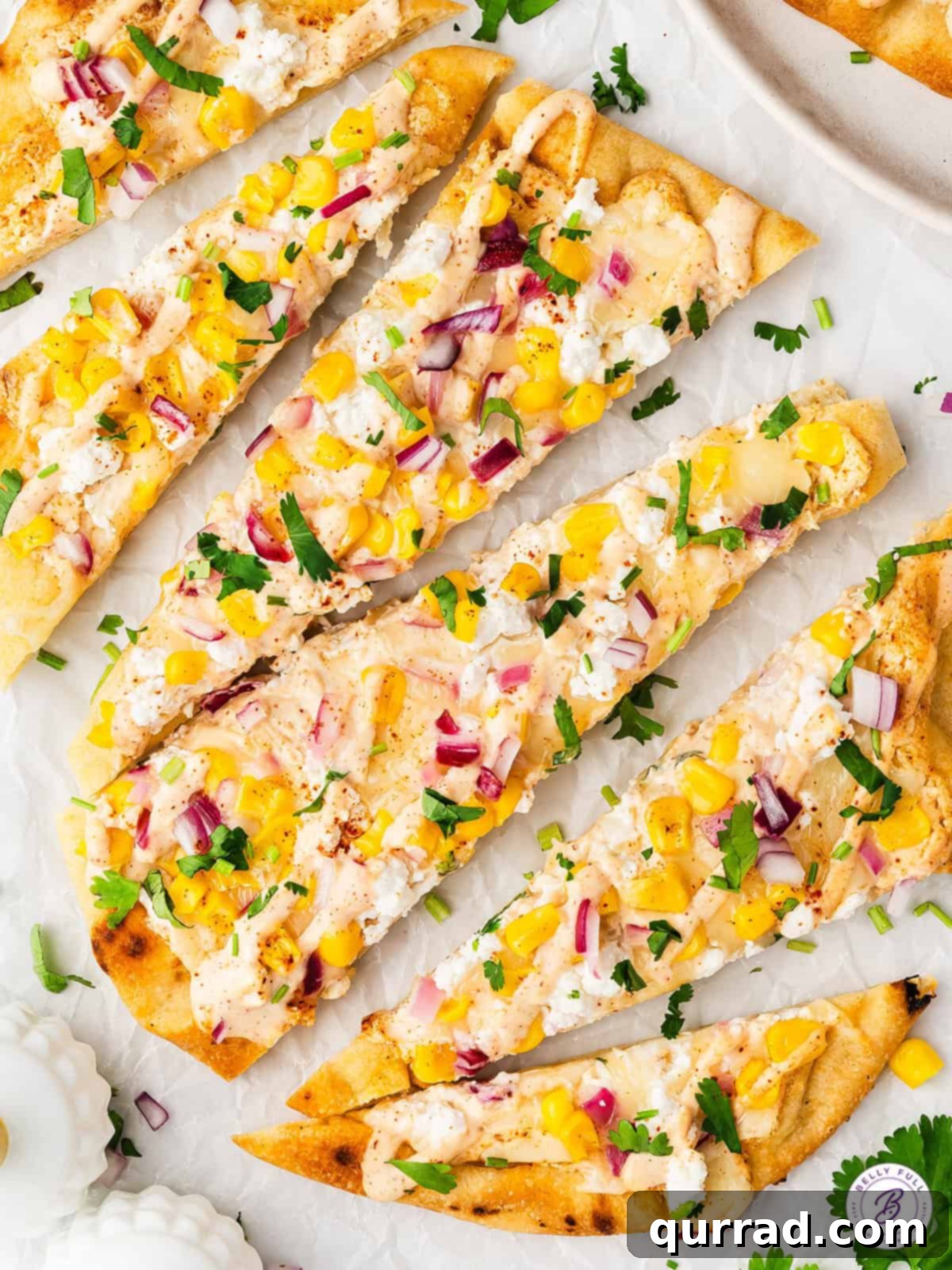 With a seasoned Mexican crema sauce, corn kernels, red onions, and lots of cheese, this Mexican Street Corn Flatbread is a fun appetizer. Street corn flatbread cut into wedges