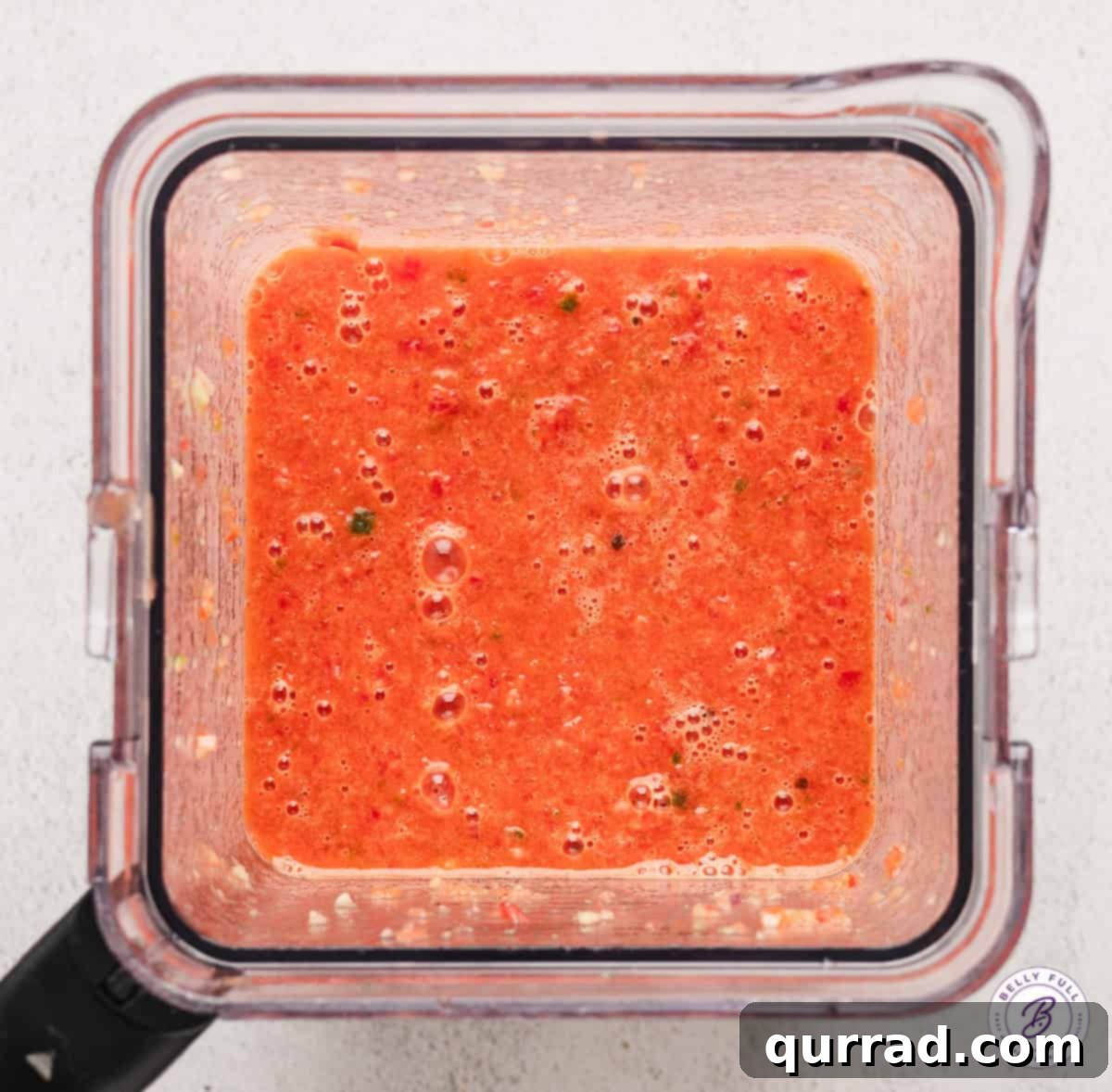 Overhead view of blended watermelon gazpacho in a blender jar, showing its smooth, pink texture.