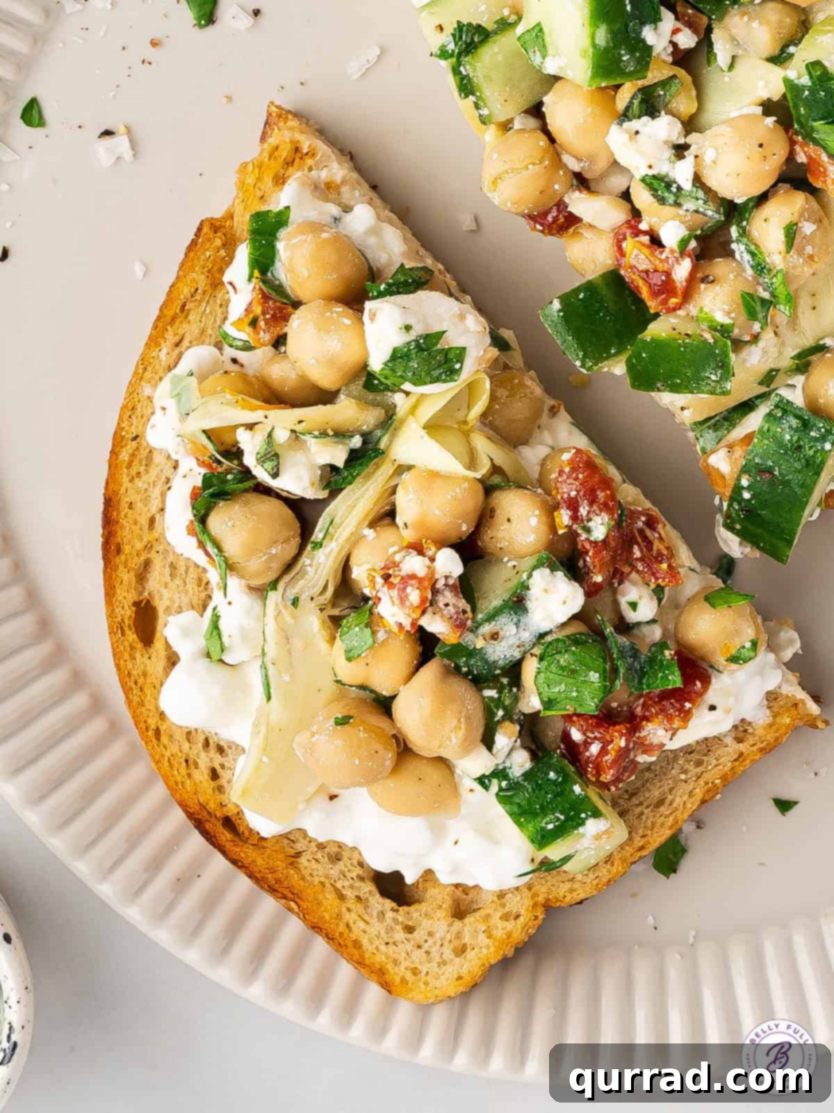 This Chickpea Salad and Cottage Cheese Toast features creamy cottage cheese on a thick slice of toast topped with a savory chickpea salad. Overhead view of chickpea salad and cottage cheese toast on a plate