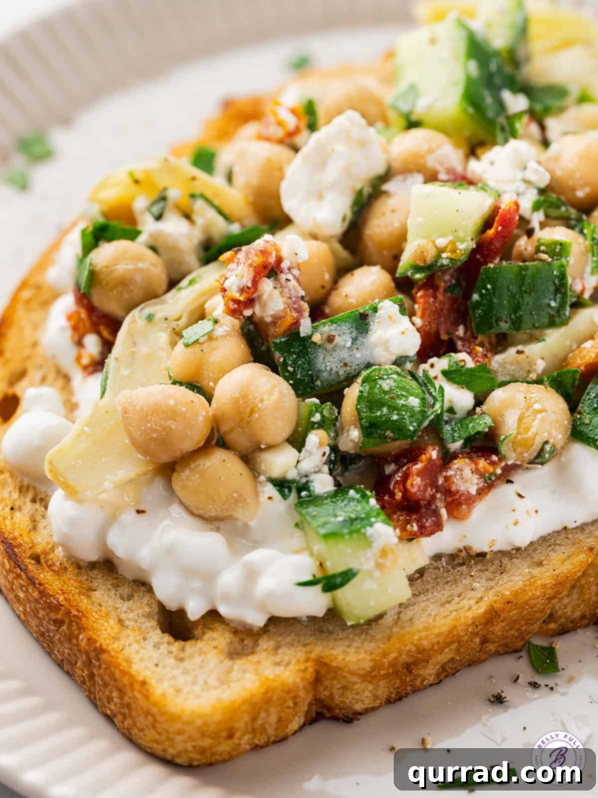 This Chickpea Salad and Cottage Cheese Toast features creamy cottage cheese on a thick slice of toast topped with a savory chickpea salad. Close up of chickpea salad cottage cheese toast