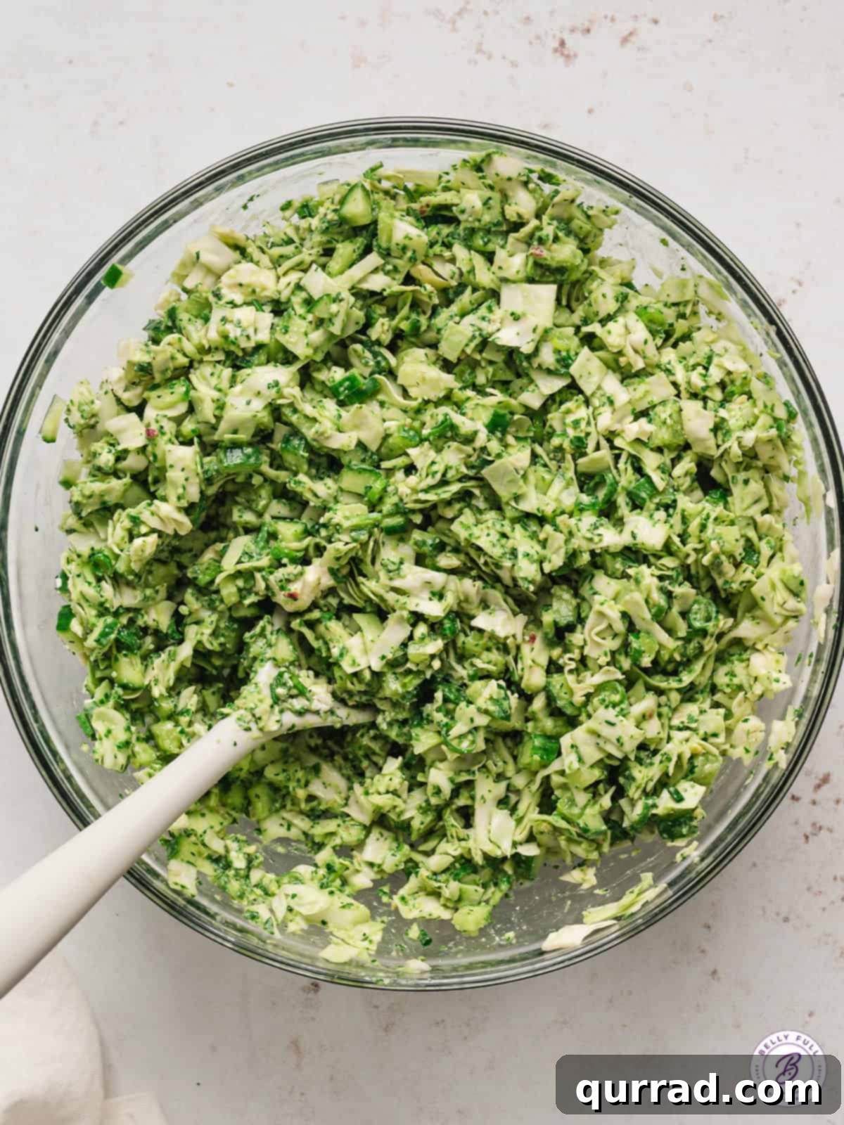 Velvet Green Goddess Salad 3 Green Goddess Salad being mixed in a large mixing bowl with a spatula, highlighting its creamy texture