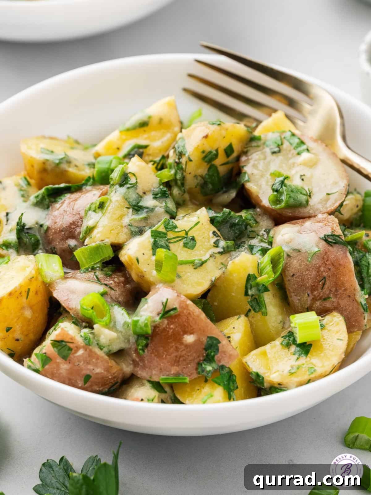 A bowl of red and yellow French Potato Salad with a fork, ready to be served.