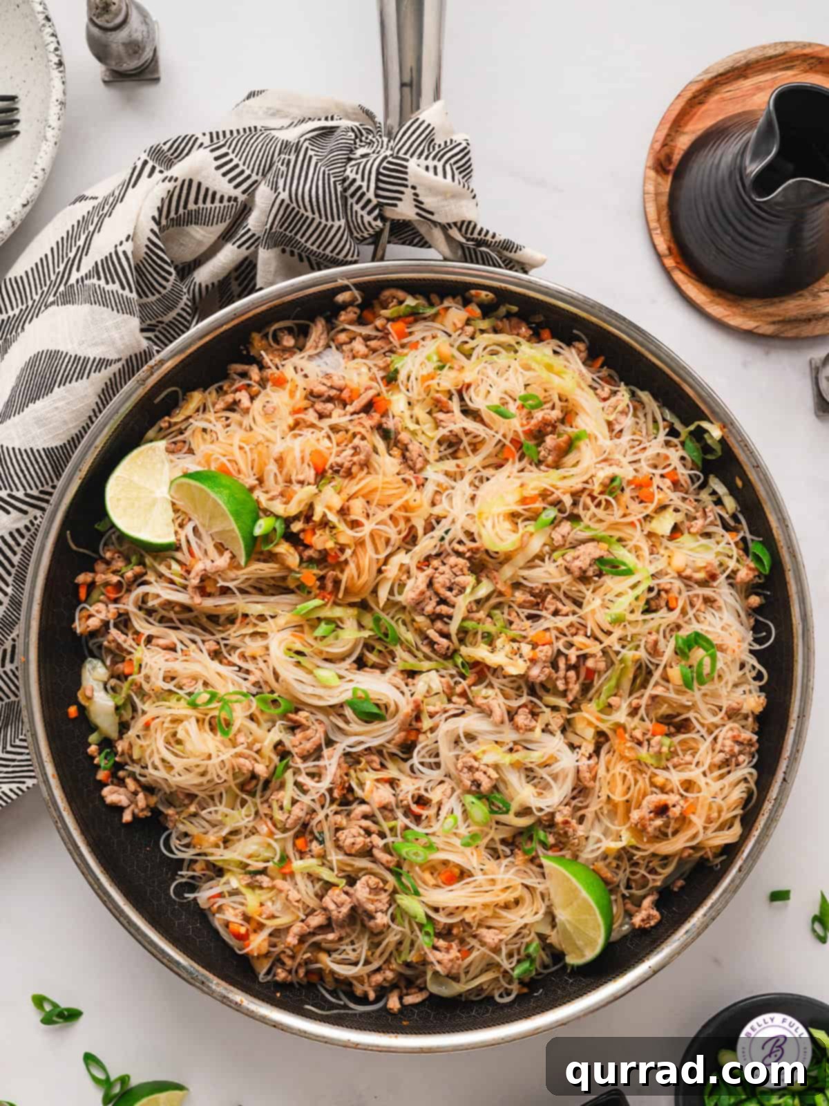An overhead shot of a large pan filled with freshly cooked Filipino Pancit, featuring ground pork, colorful vegetables, and rice noodles bathed in a rich, savory sauce.