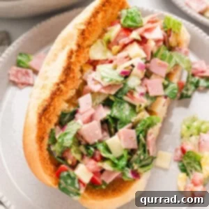 An Italian chopped salad sandwich on a plate with vibrant ingredients